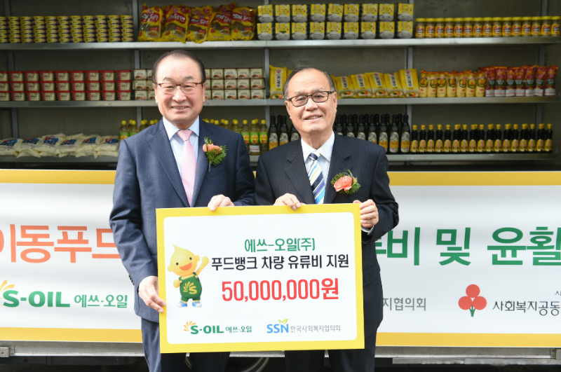 S-OIL 신동열 부사장(왼쪽)이 한국사회복지협의회 최일섭 부회장에게 S-OIL 푸드뱅크 차량 유류비 후원금 기부 판넬을 전달하고 농어촌 소외지역에 식료품을 배달할 푸드뱅크 차량 앞에서 기념촬영을 하고 있다.