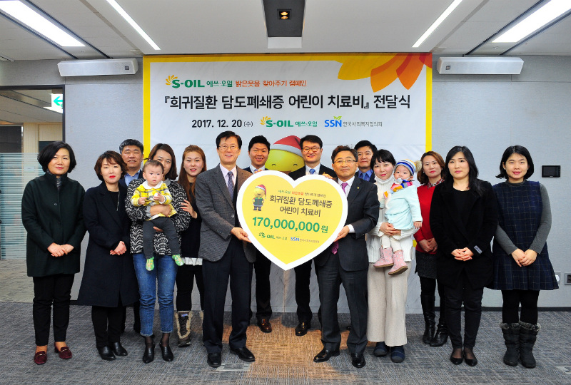 S-OIL 이창재 부사장 (앞줄 왼쪽 다섯 번째)이 한국사회복지협의회 서신일 부회장 (네 번째)에게 담도폐쇄증 환아를 돕기 위한 임직원 급여우수리 모금액을 전달한 뒤 수혜 가족 및 관계자들과 기념촬영을 하고 있다.