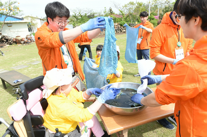 캠프에 참가한 어린이들이 가족, 봉사자들과 함께 천연 염색 체험을 하며 즐거운 시간을 보내고 있다.
